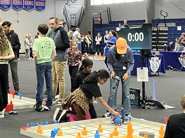 Students place a robot on the competition field.